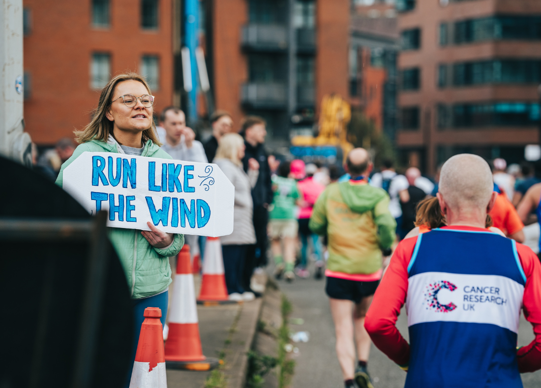 women supporting runner with sign saying run like the wind